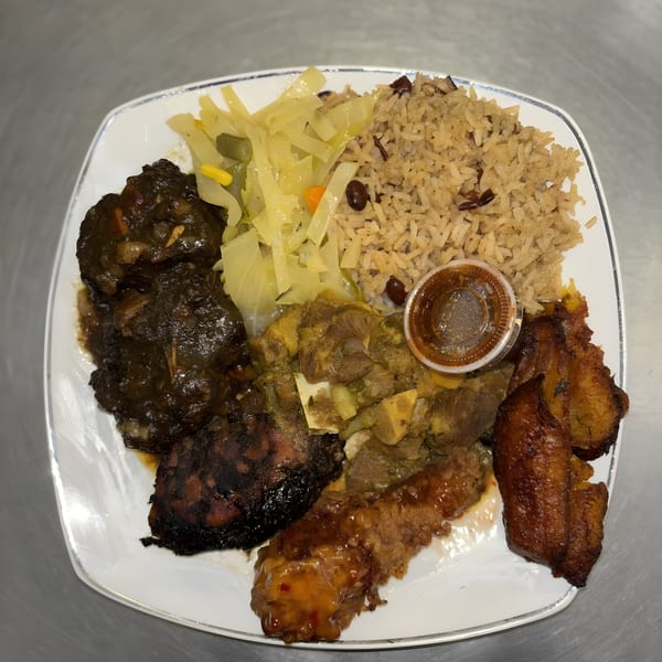 A white plate filled with Jamaican brown stew chicken, curry goat, rice and peas, cabbage, and plantains.