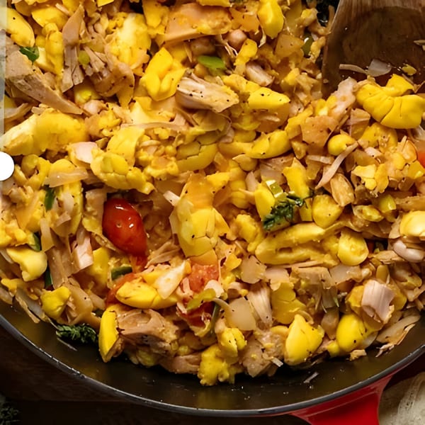 Close-up of Jamaican ackee and saltfish with vegetables in a red skillet.