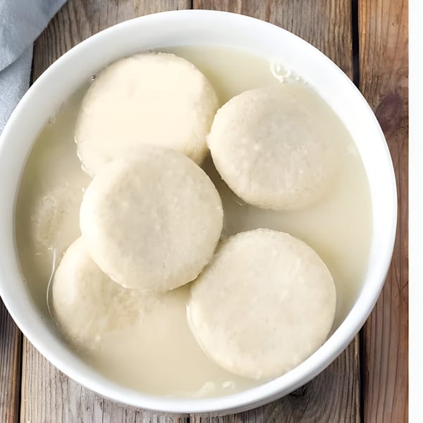 A white bowl filled with five round, light-colored dumplings submerged in a clear liquid.